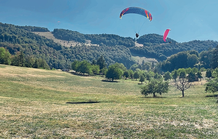Gleitschirm-Pilotinnen und -Piloten im Zielgelände in Lauwil. Im Hintergrund ist das Startgebiet auf der Hohwacht gut zu erkennen.Fotos: M. Stöcklin