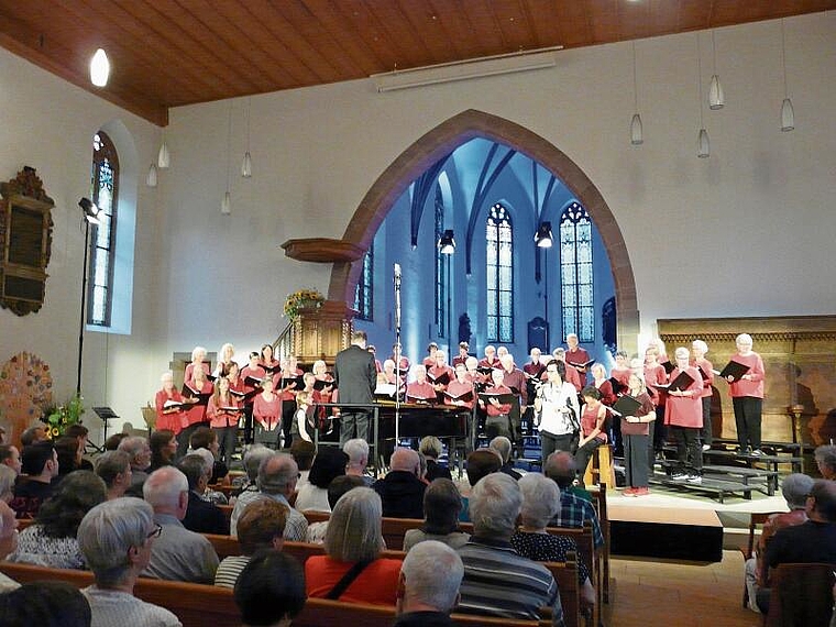 Die Singstimmen Baselland ganz in Rot gekleidet mit ihrem Dirigenten Jürg Siegrist und der Moderatorin Regi Sager.  Foto: A: Jegge