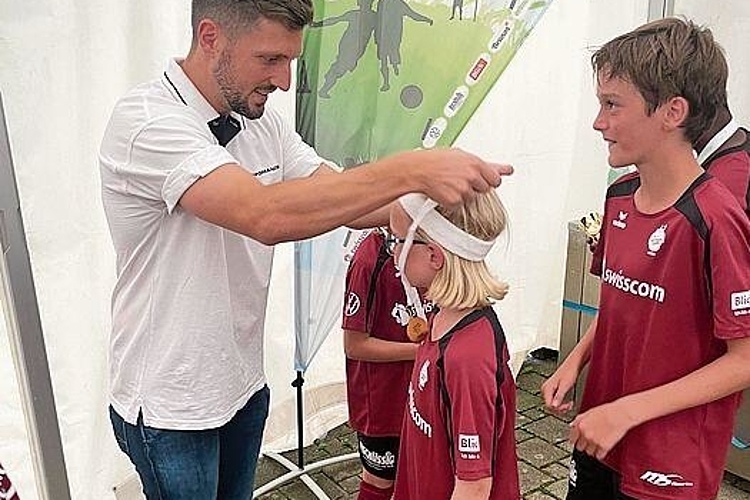 Simon Grether überreicht den Kindern eine Gold-Medaille.