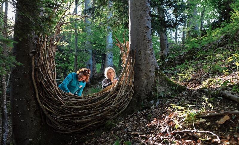 «Parallel-Perspektive-Kontinuität» von Sandra Huber und Heidi Binggeli, Schweiz, tote Zweige aus der Umgebung. Heidi Binggeli und Sara Huber, zwei Floristinnen aus der Schweiz, haben dieses Werk gemeinsam geschaffen. Es besteht aus zwei U-förmigen Geflechten mit Öffnung nach oben, jedes angebracht zwischen zwei Bäumen. Diese Bäume stehen in einem Waldstück am Hang. Sie wurden so gewählt, dass sie eine Parallele bilden und somit eine Tiefenperspektive ermöglichen, wie es der Titel sagt.  Die Wiederholung der beiden Geflechte soll aber auch Kontinuität darstellen – der ewige Kreislauf des Werdens und Vergehens.