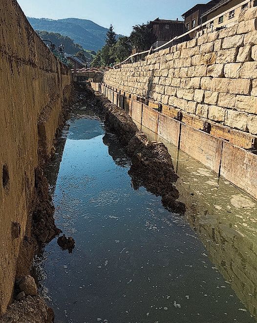 Das ruhige Gewässer der Hinteren Frenke. Links im Bild eine Winkelstützmauer, die strassenseitig gebaut wird. Im Hintergrund erkennt man eine Schwergewichtsmauer.